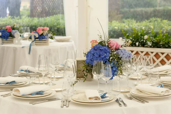 White round dinner tables stand served with blue bouquets