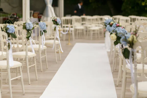 Weißer Weg verläuft zwischen den mit blauen Blumen geschmückten Stühlen — Stockfoto