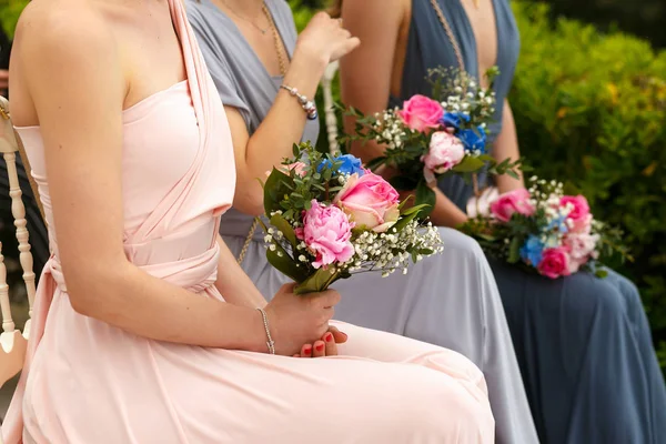 Damas de honor en elegantes vestidos de pastel se sientan con ramos de boda — Foto de Stock