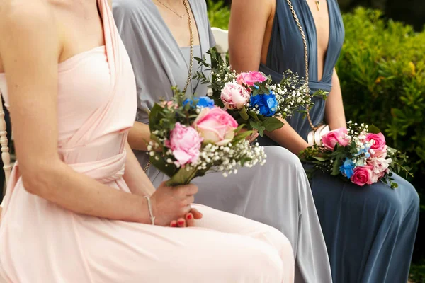 Bouquets de casamento rosa jazem sobre os joelhos de damas de honra em pastel — Fotografia de Stock