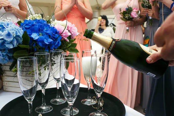 Les invités se tiennent autour de la table pendant que l'homme verse le champagne — Photo