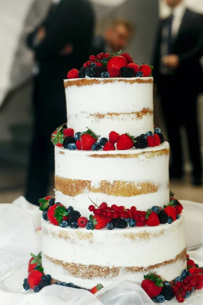 Bayas rojas y negras decoran pastel de boda blanco — Foto de Stock
