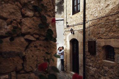 Gül duvarın arkasından bir öpüşme düğün çift üzerinde bak