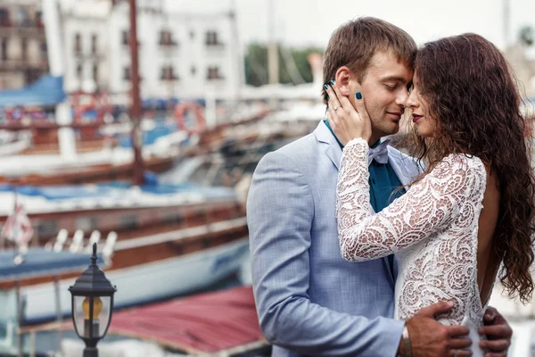 Kudrnatá brunetka v bílých šatech drží tvář zadávací zatímco on h — Stock fotografie