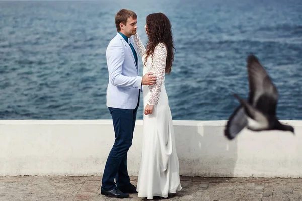 Duvor flyga runt vackra par stående vid havet — Stockfoto