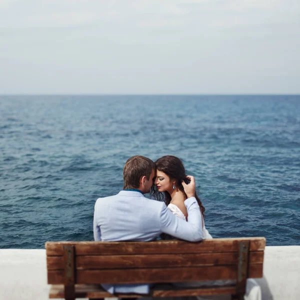 Hinreißende Dame lehnt sich an einen Mann, während sie auf dem Liegeplatz am Meer sitzt — Stockfoto