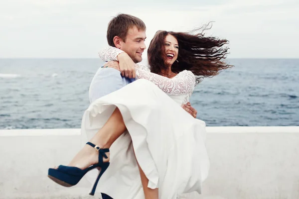 Жених кружит невесту в синих туфлях на берегу моря — стоковое фото