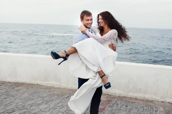 Novia en zapatos azules sonríe mientras el novio la sostiene en sus manos —  Fotos de Stock