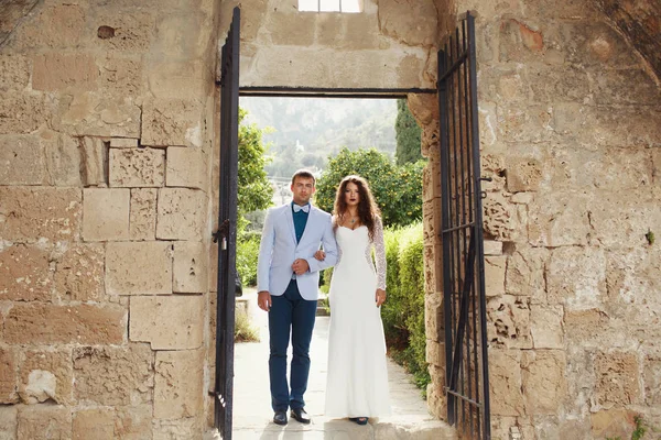 Stilvolles Brautpaar steht vor alten Steintoren — Stockfoto
