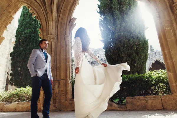 Braut wirbelt vor einem Bräutigam unter den Steinbögen — Stockfoto