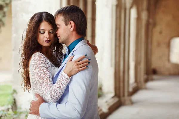 Noiva segura suas mãos sobre os ombros do noivo largo vestido com bl — Fotografia de Stock
