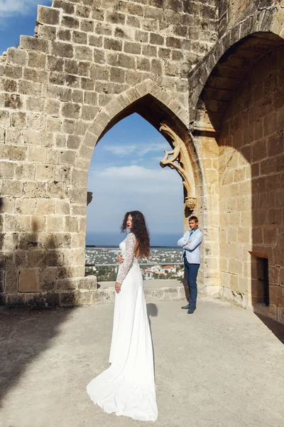 Sposa in bellissimo abito lungo passeggiate a uno sposo lungo le rovine — Foto Stock