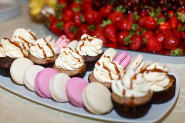 Karamel ve pembe macaroons yalan beyaz tabakta ile cupcakes