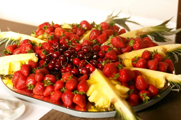 Ananas, třešně a jahody leží na skleněnou desku — Stock fotografie