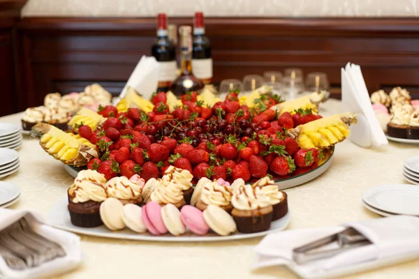 Fruits and pink sweets stand served on the table covered with wh — Stock Photo, Image