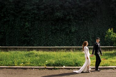 Damat ve gelin şık elbiseli olan yol üzerinde Parkta yürümek