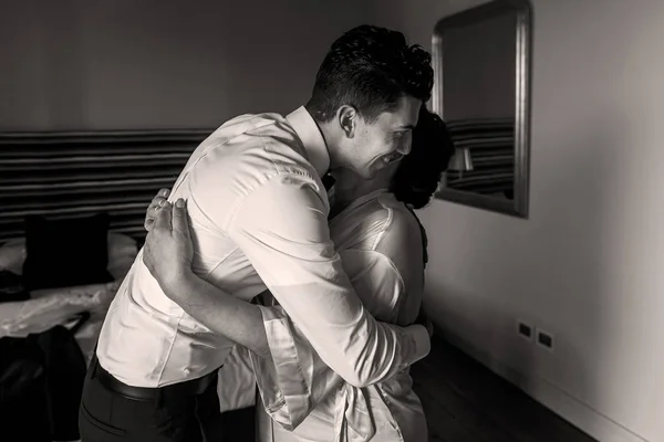 Nuori mies halaa äitiään seisomassa hotellihuoneessa — kuvapankkivalokuva