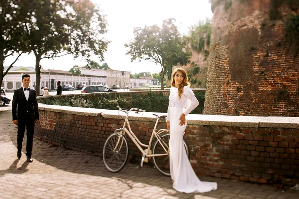 In zwarte smoking wandelingen aan een elegante bruid bruidegom — Stockfoto