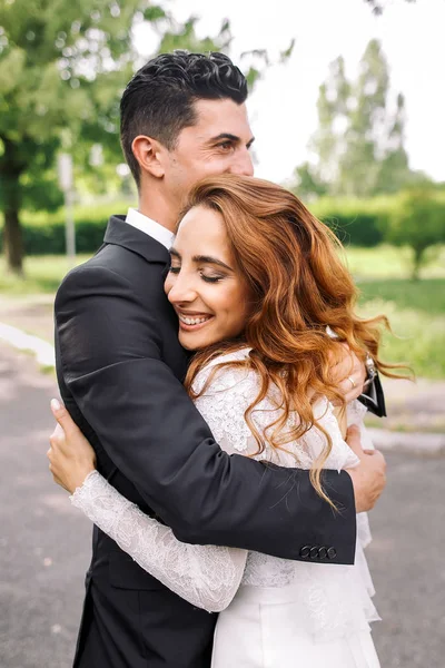Lady with broad smile and long curly hair leans to a man in blac — Stock Photo, Image