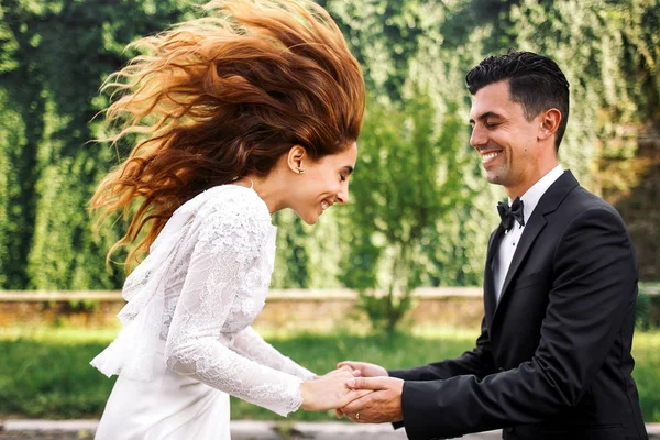 Brudgummen håller händerna bruden hoppning före honom — Stockfoto