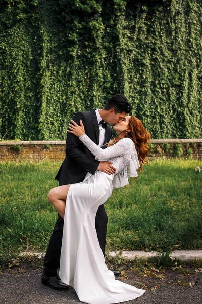 Noivo dobra noiva e beija-la apaixonadamente no parque — Fotografia de Stock