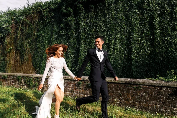 Sposo guarda una splendida sposa con i capelli volanti mentre corrono — Foto Stock