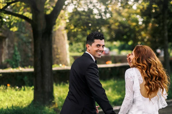 Bruidegom kijkt over zijn schouder terwijl bruid hem lacht — Stockfoto