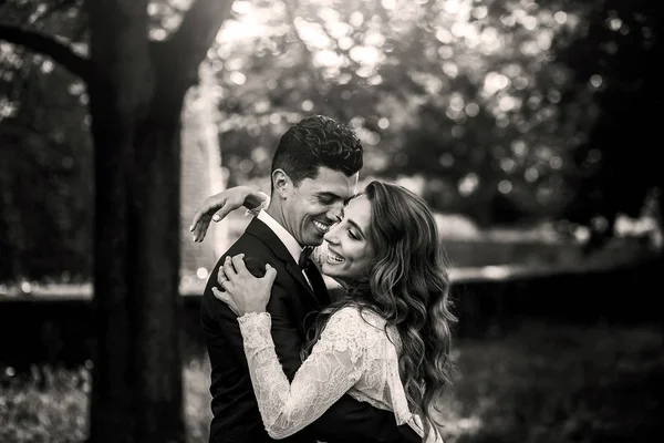 Foto em preto e branco do noivo sorridente segurando a noiva rindo — Fotografia de Stock