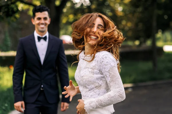 Smiling bride dances before a groom mixing her hair actively — Stock Photo, Image