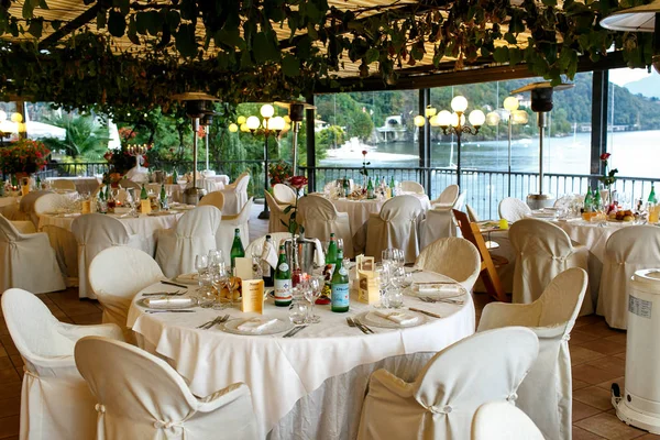 White chairs covered with white cloth stand in the restaurant ov