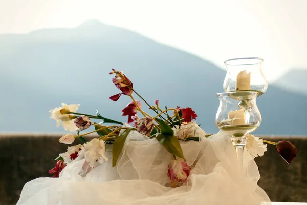 Gafas de vino con velas blancas alrededor de ramo blanco — Foto de Stock