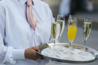 Suyu ve şampanya ile gözlük tarafından düzenlenen çelik tepsi üzerinde durmak