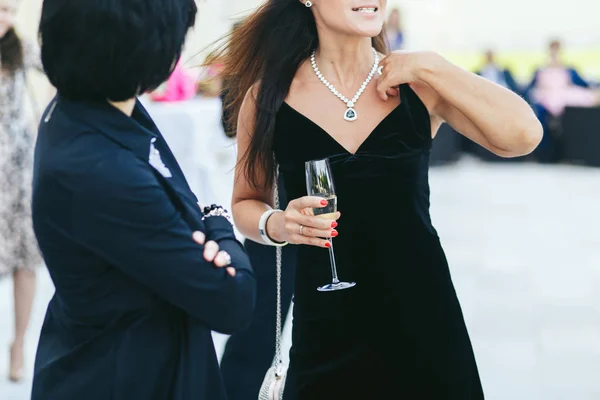 Вітер дує волосся жінки, а вона тримає келих шампанського — стокове фото