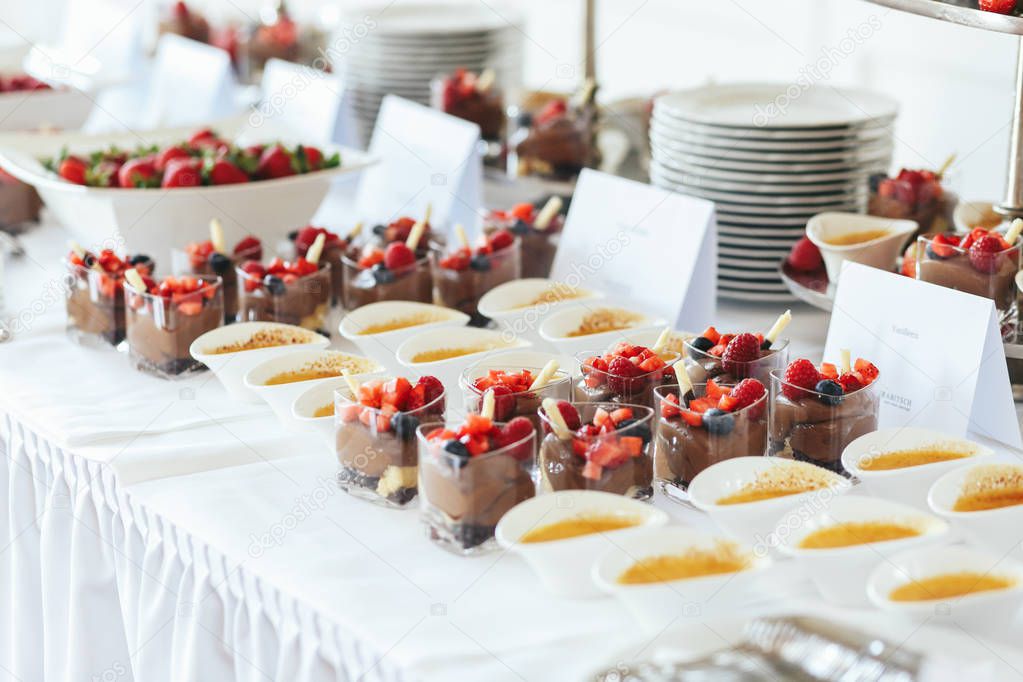 Bowls with sauces and glasses with chocolate desserts stand on t