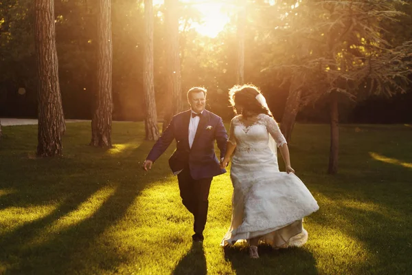Die Sonne scheint über die lockige Braut, die über den Rasen läuft — Stockfoto