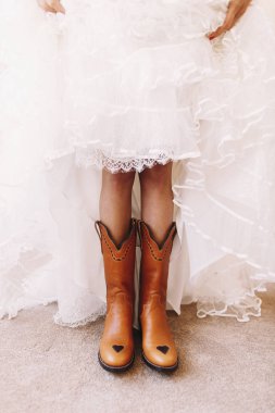 Bride raises her skirt to show the boots under it clipart