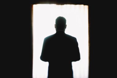 Bir adam karanlık parlak bir pencerede önce ayakta silüeti 