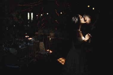 Gelin ve damat karanlık hangarda ışınlarının içinde öpüşme standı 