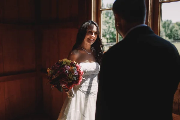 Boldog menyasszony mosolyog a vőlegény, miközben köszönti őt mögött egy világos — Stock Fotó