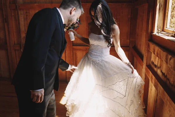 Groom regarde la robe de mariée pendant qu'ils se tiennent dans le hangar — Photo