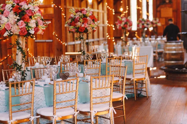 Long tables covered with blue clothes stand in the wooden hangar