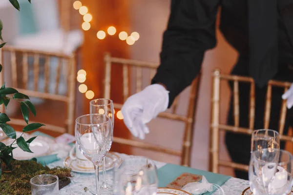 Serveur en gants blancs ajuste la verrerie sur la table à manger — Photo