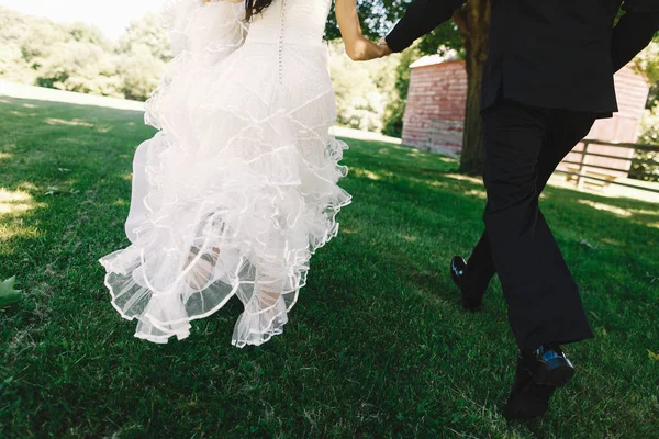 Bride's curly skirt whirls while she walks with a groom on the l — Stock Photo, Image