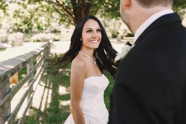 Lachende bruid met perfecte witte tanden kijkt naar een bruidegom terwijl po — Stockfoto