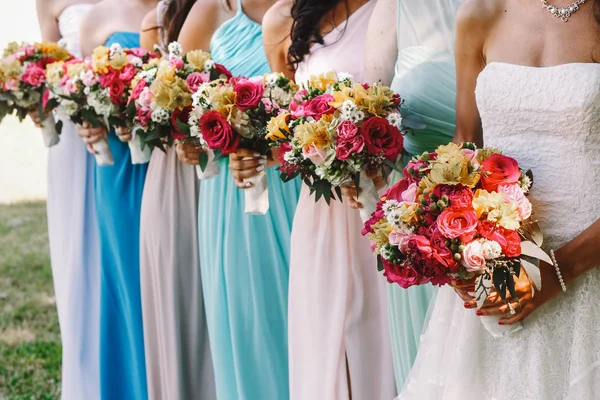 Novia y damas de honor celebrar ramos de boda en una fila, mientras que posin —  Fotos de Stock