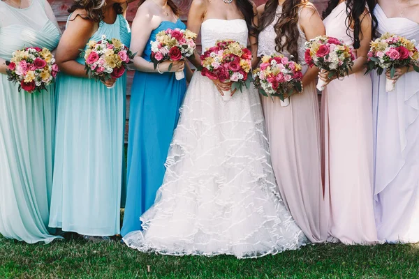 Sposa e damigelle d'onore con mazzi di fiori di nozze luminosi stand sul — Foto Stock