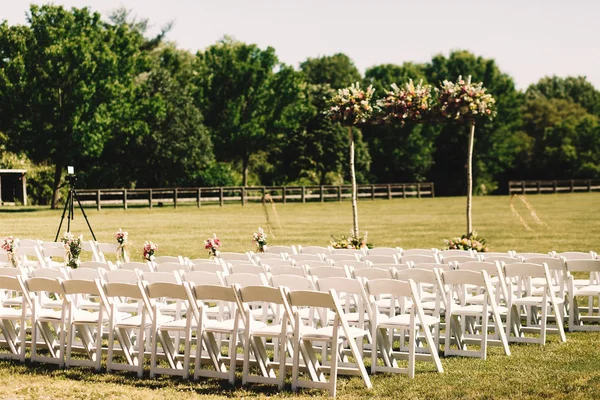 Muchas sillas blancas se colocan en filas ante un altar de bodas en la fi — Foto de Stock