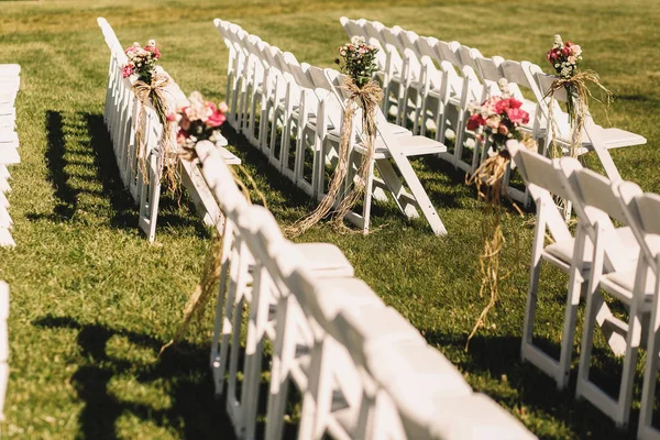 Белые стулья стоят в длинных рядах, ожидая начала свадьбы — стоковое фото