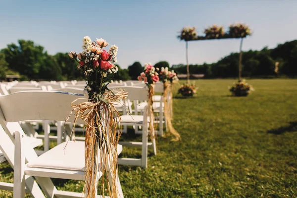 Ροζ ανθοδέσμες ομορφύνει λευκές καρέκλες που στέκεται πριν από το γάμο — Φωτογραφία Αρχείου