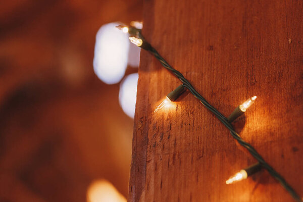 Closeup of light garland twined around the wooden pillar